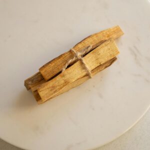 A top view of tied Palo Santo sticks placed on a round marble plate. Ideal for wellness themes.