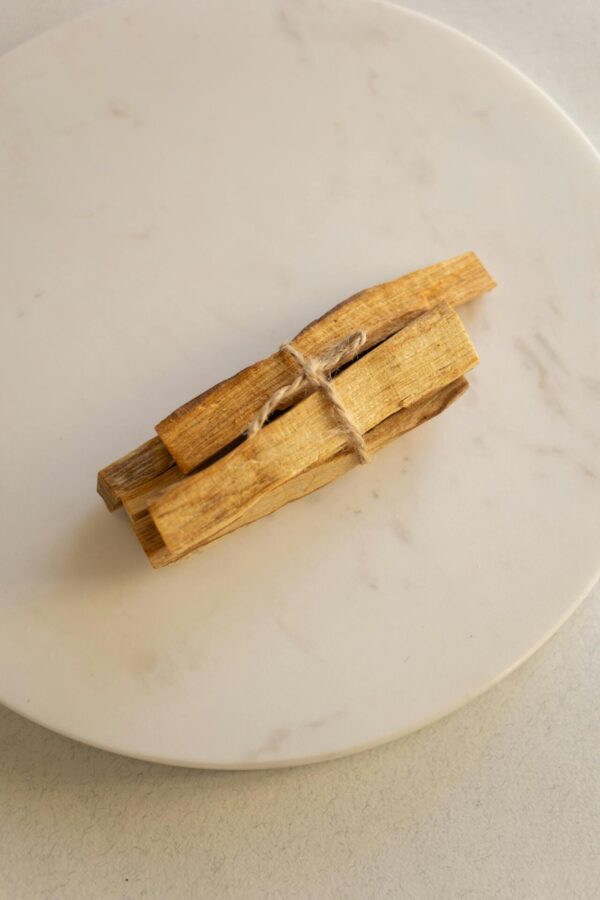A top view of tied Palo Santo sticks placed on a round marble plate. Ideal for wellness themes.
