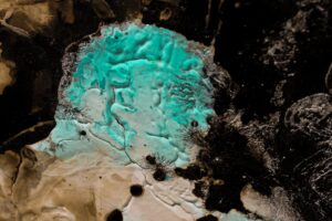 Close-up of abstract textured artwork with striking turquoise, brown, and black colors.